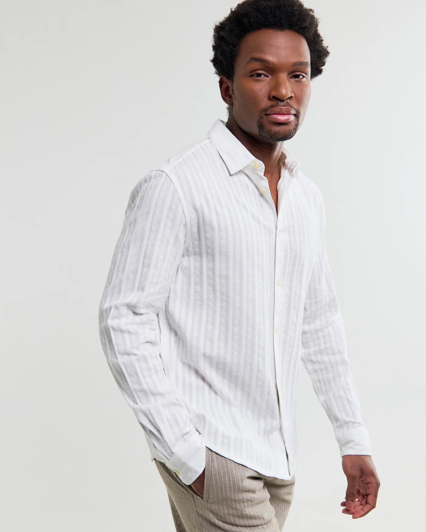 Man wearing Wax London Dartford long sleeve shirt with subtle dobby stripe pattern in white, styled with beige trousers.