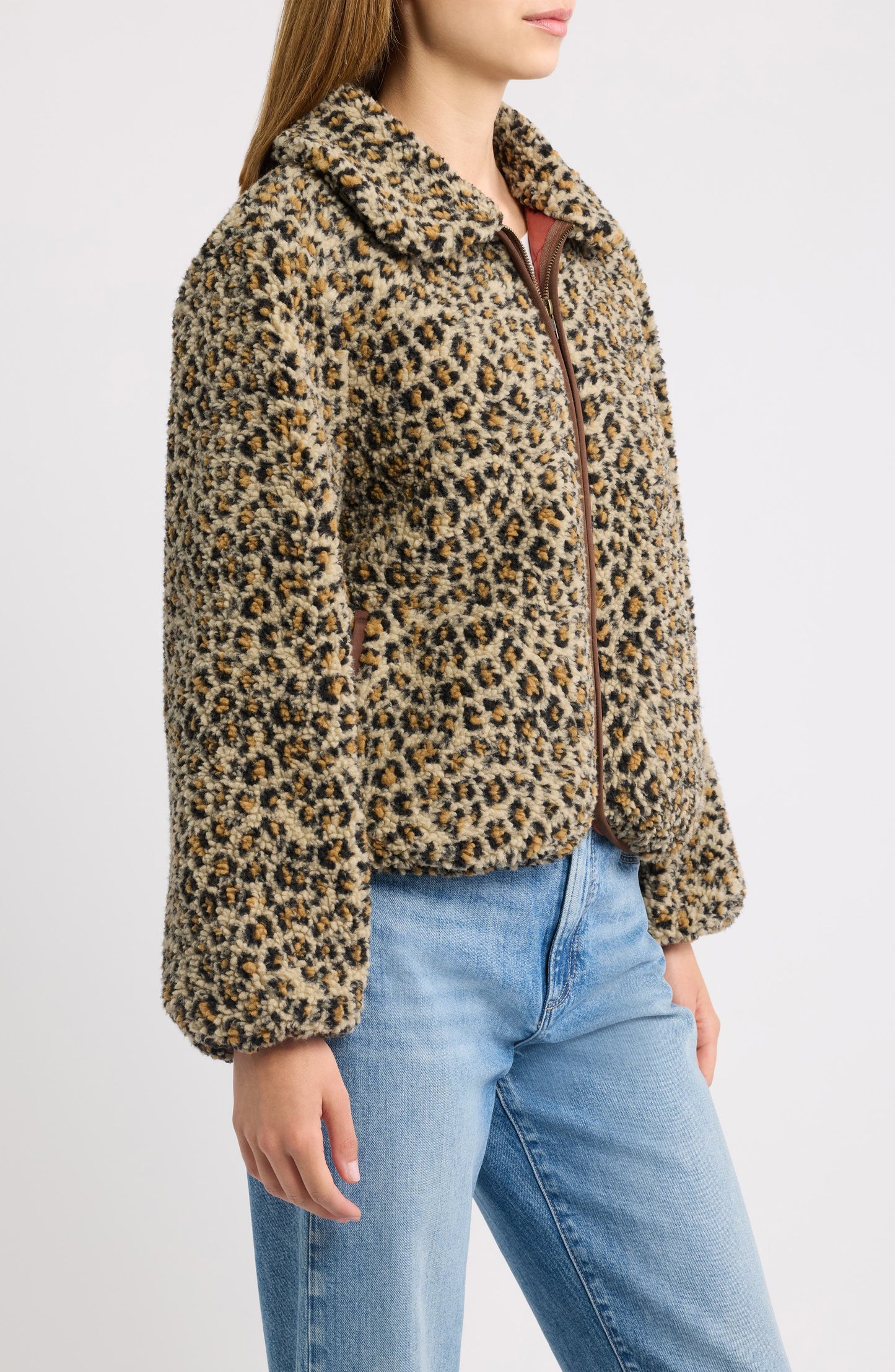 Model wearing tan leopard print fleece zip jacket with blue jeans