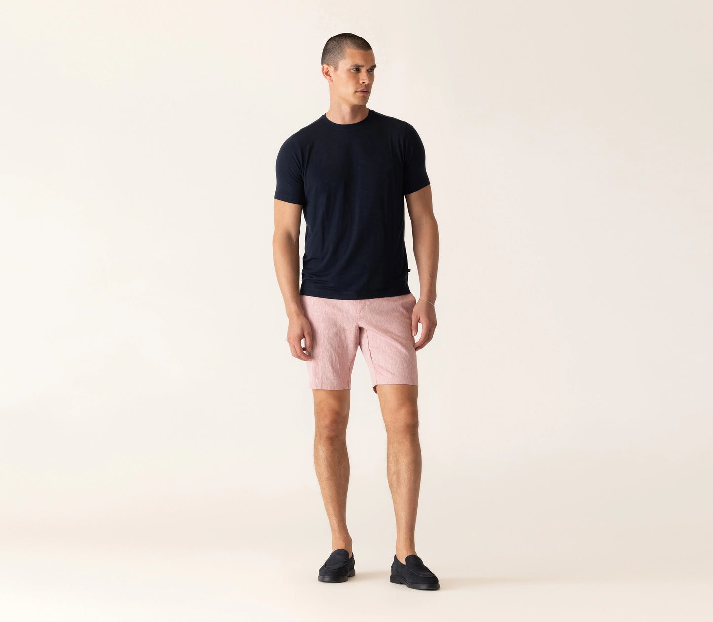 Man wearing Deke SS Modern Crew T-Shirt in midnight black with pink linen shorts and black loafers.