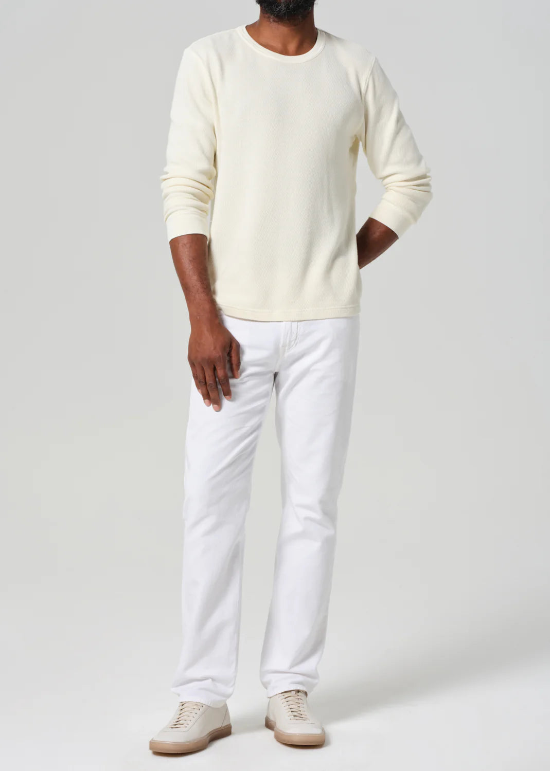 Citizens of Humanity white stretch linen Elijah jeans worn by male model with cream sweater and sneakers