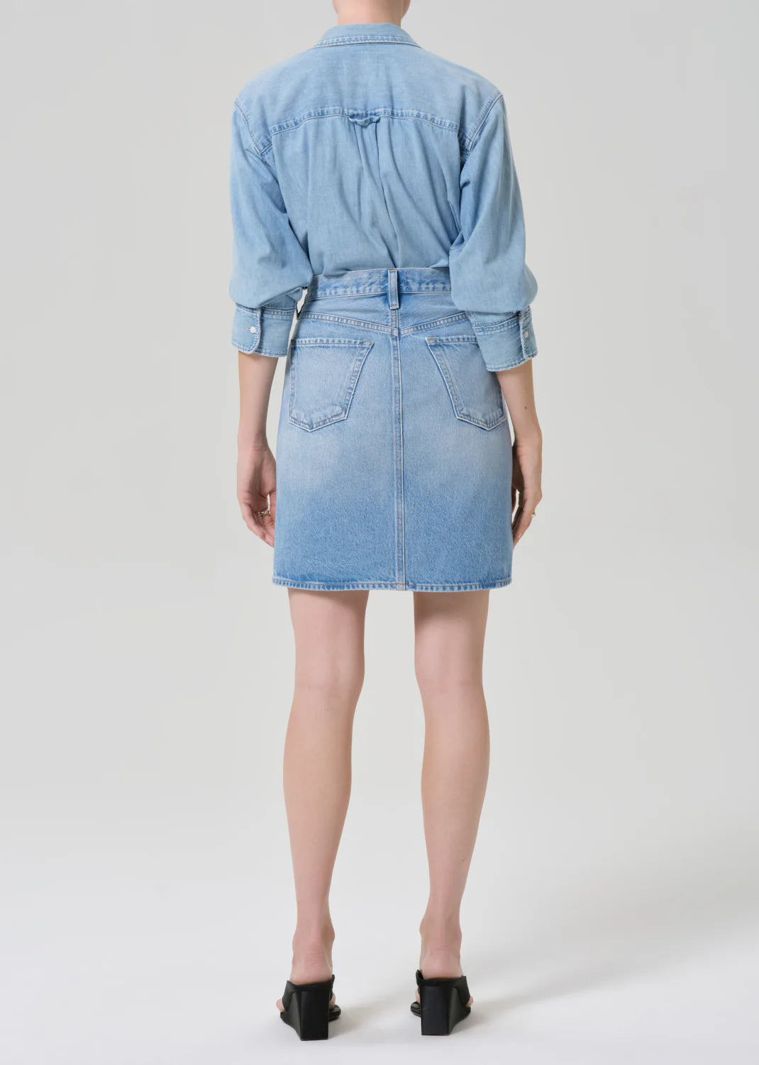 Citizens of Humanity Etta Pencil Skirt in light blue denim, shown from behind with matching denim shirt and black heels.