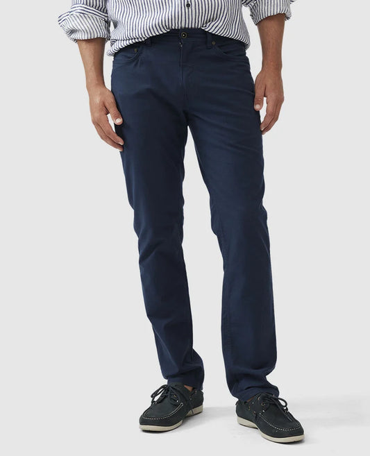 Rodd & Gunn navy five-pocket pants worn by model with striped shirt and boat shoes