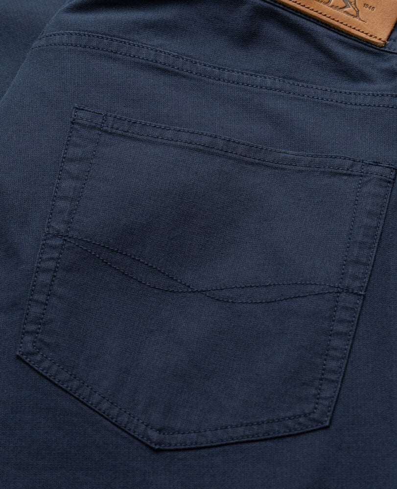 Close-up of Rodd & Gunn navy five-pocket pants showing detailed back pocket stitching and leather waistband label.