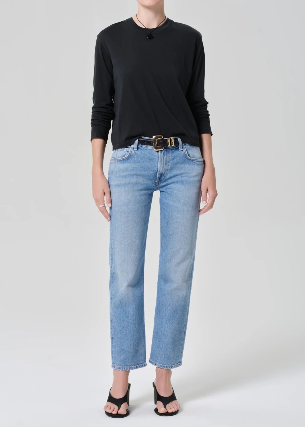 Woman wearing Citizens of Humanity Anissa jeans in Flutter wash with black long-sleeve top and belt