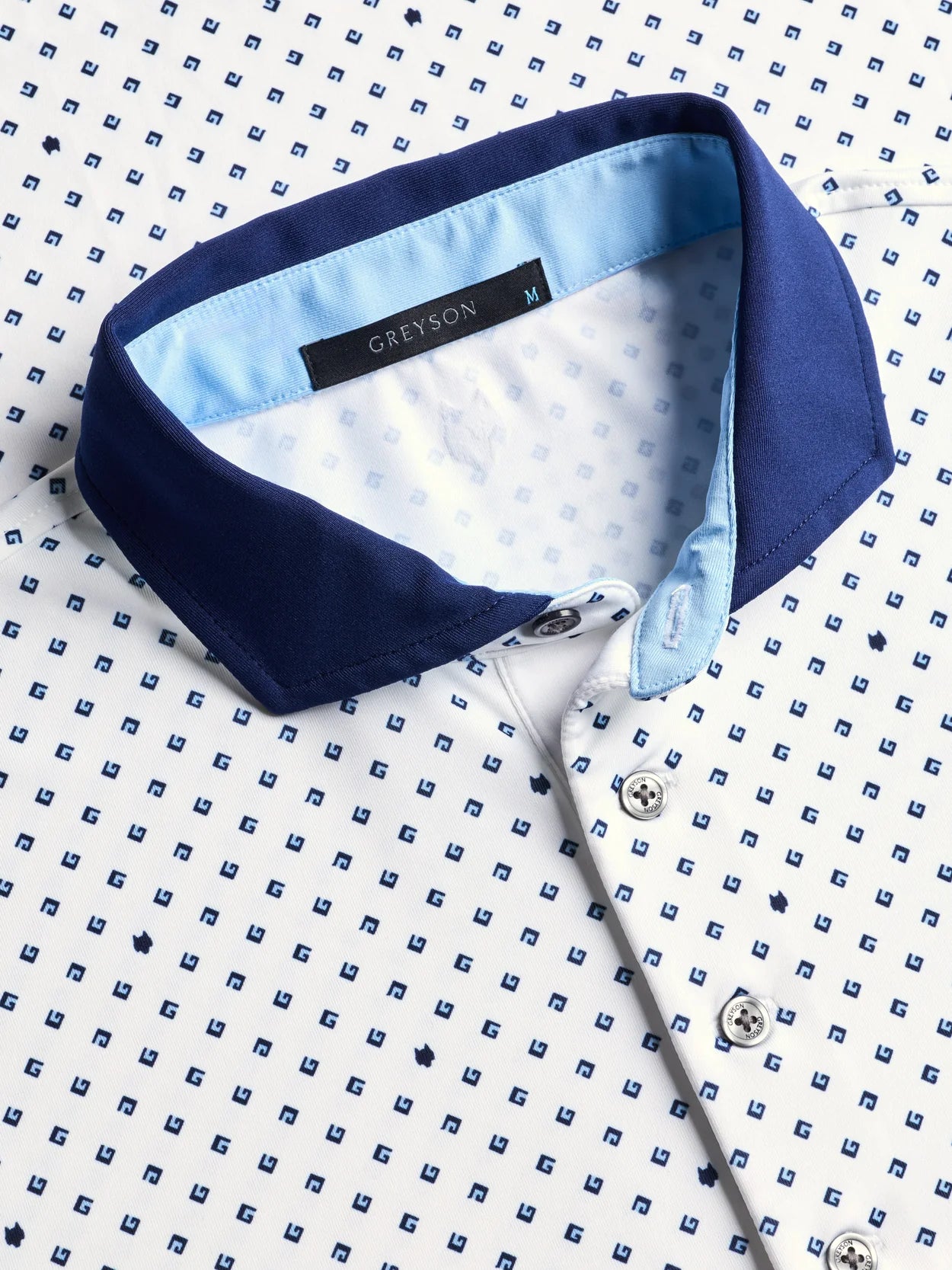 Greyson G Squared Polo in Arctic colorway featuring white fabric with blue G letter pattern and navy collar trim.