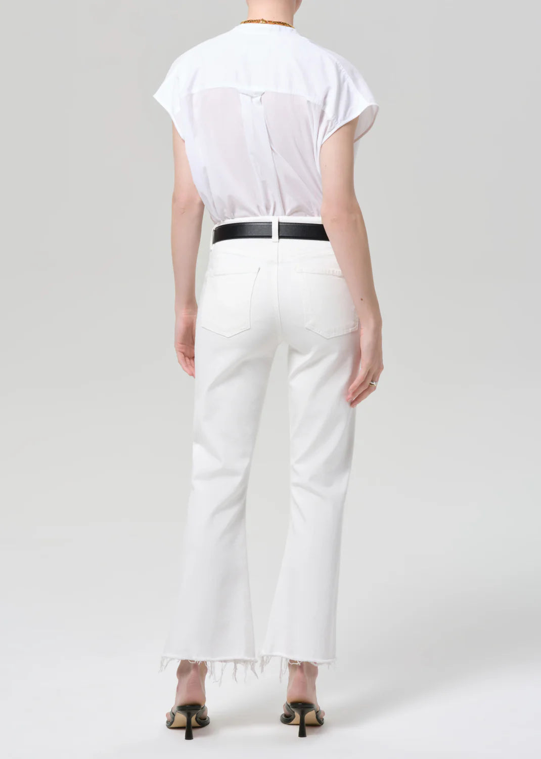 Back view of Citizens of Humanity Goldie Kick Flare jeans in white with raw hem and black belt.
