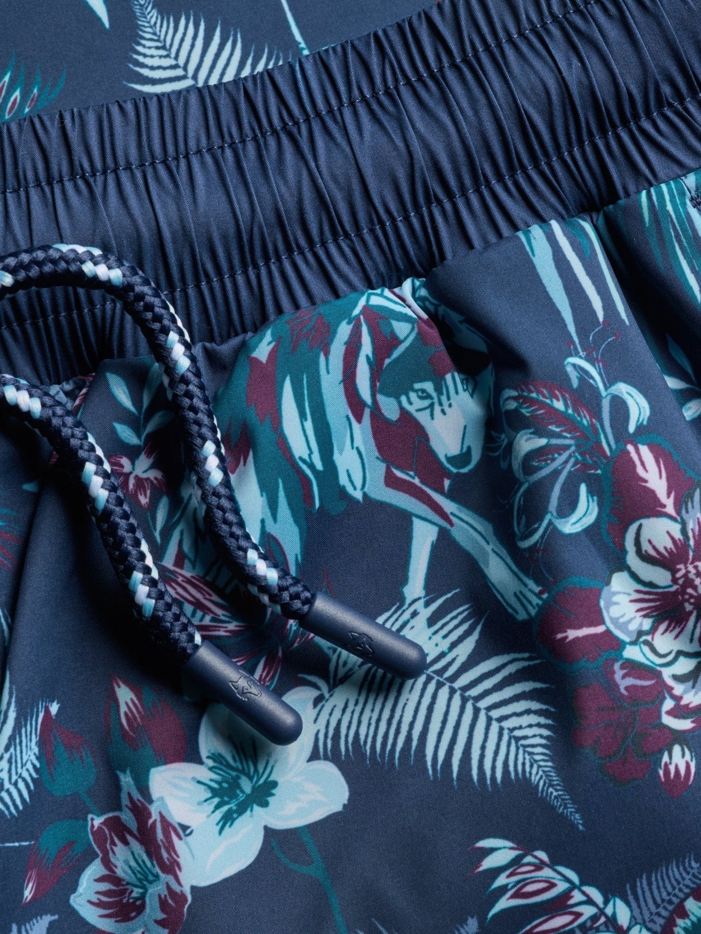 Navy blue swim shorts with tropical floral pattern and drawstring waistband detail