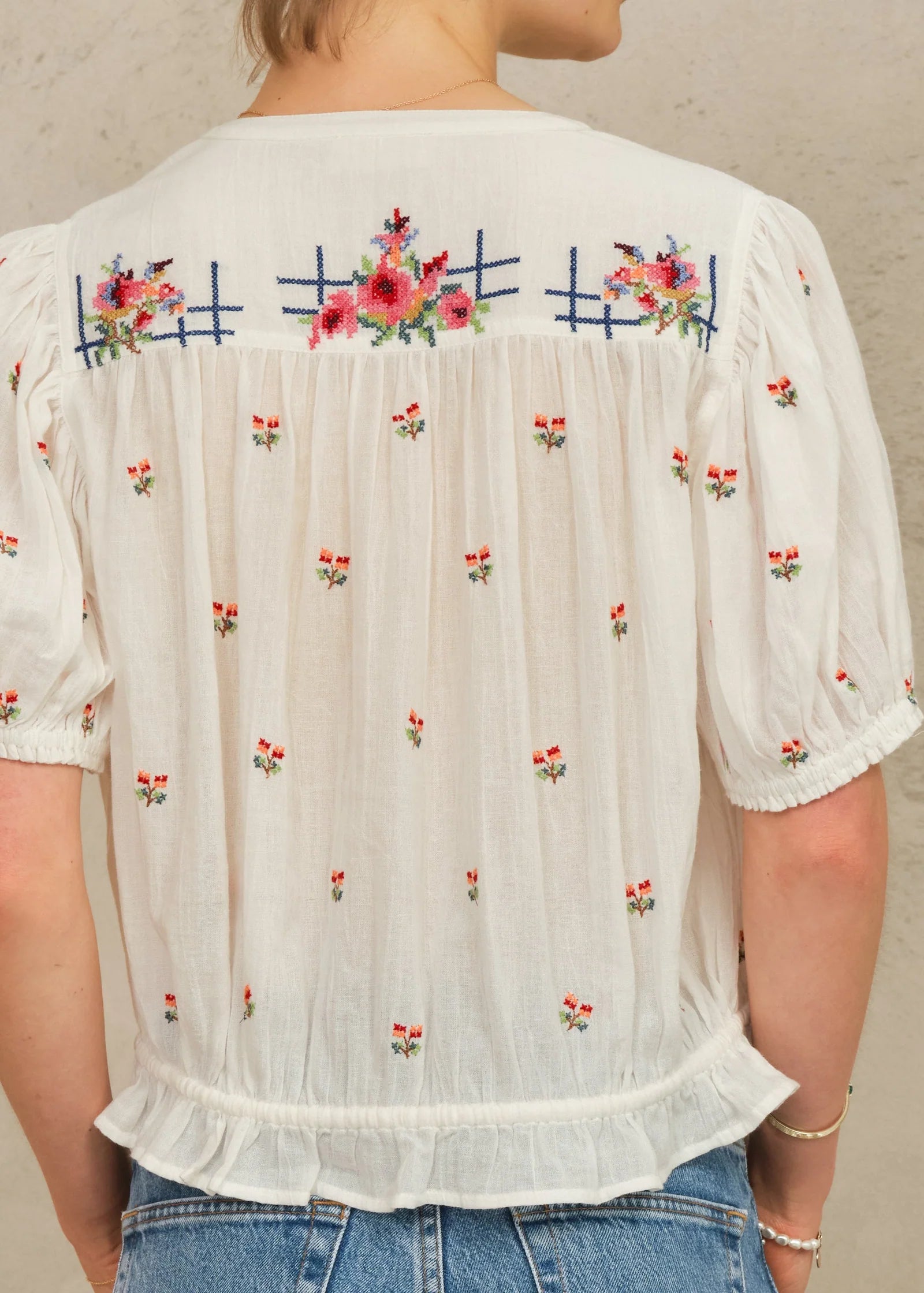 MABE Harlie embroidered short sleeve top in ecru with colorful floral cross-stitch pattern and ruffle details