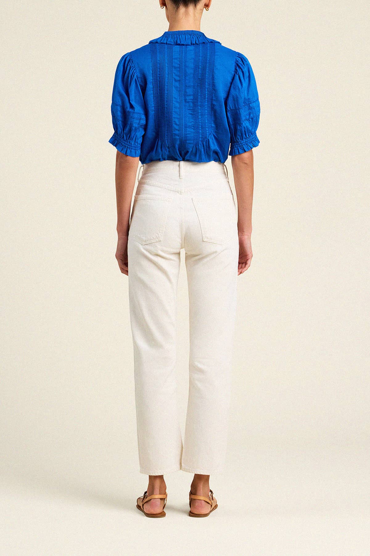 Trovata Jess cropped blouse in cobalt blue with puff sleeves and pintuck detailing, shown from behind with white jeans.