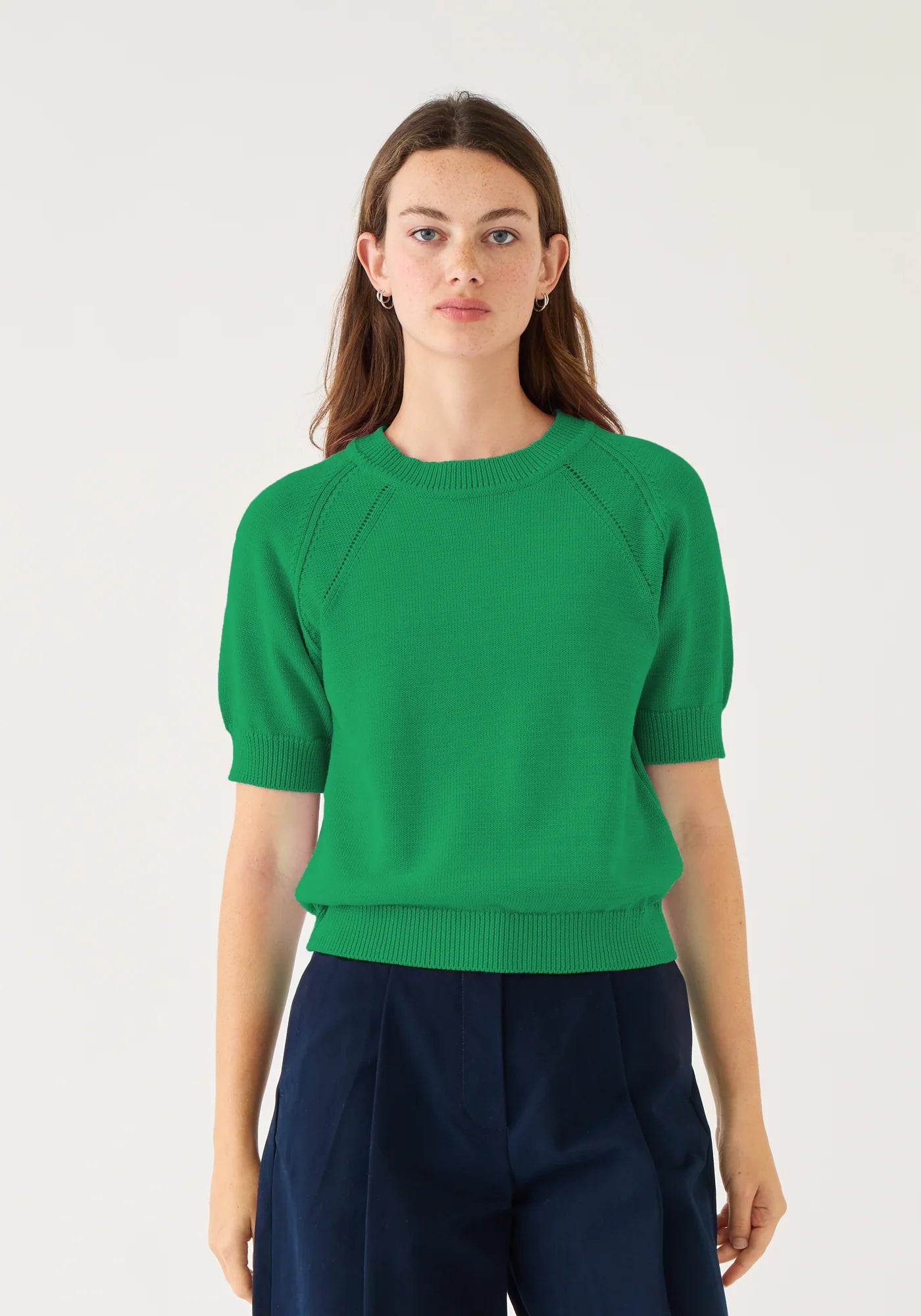 Demylee Arden short-sleeve green knit sweater with ribbed cuffs and hem on model wearing navy skirt