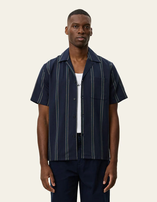 Les Deux Lawson short-sleeve striped shirt in dark navy with vertical stripes, worn open over white tee.