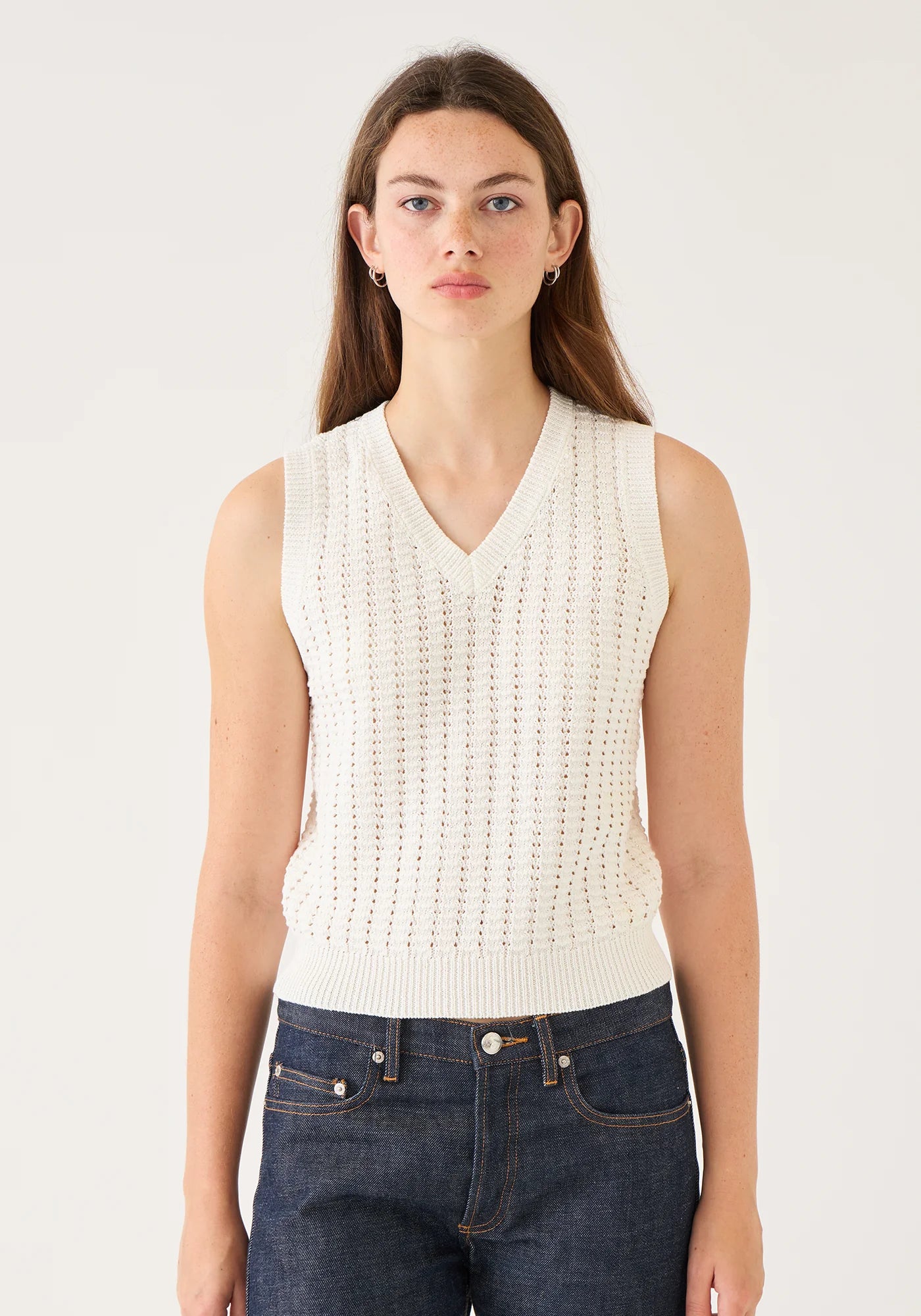 Demylee Layla sleeveless cotton crochet sweater vest with V-neck in off white, styled with dark jeans.