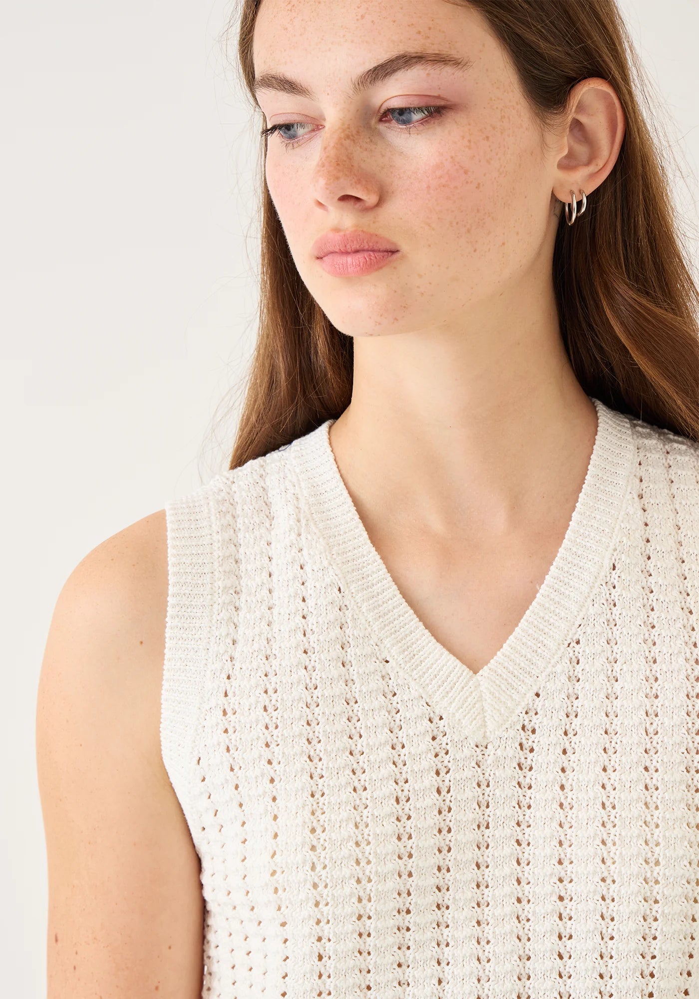 Woman wearing Demylee Layla sleeveless cotton crochet top with V-neck and eyelet knit pattern in cream white.