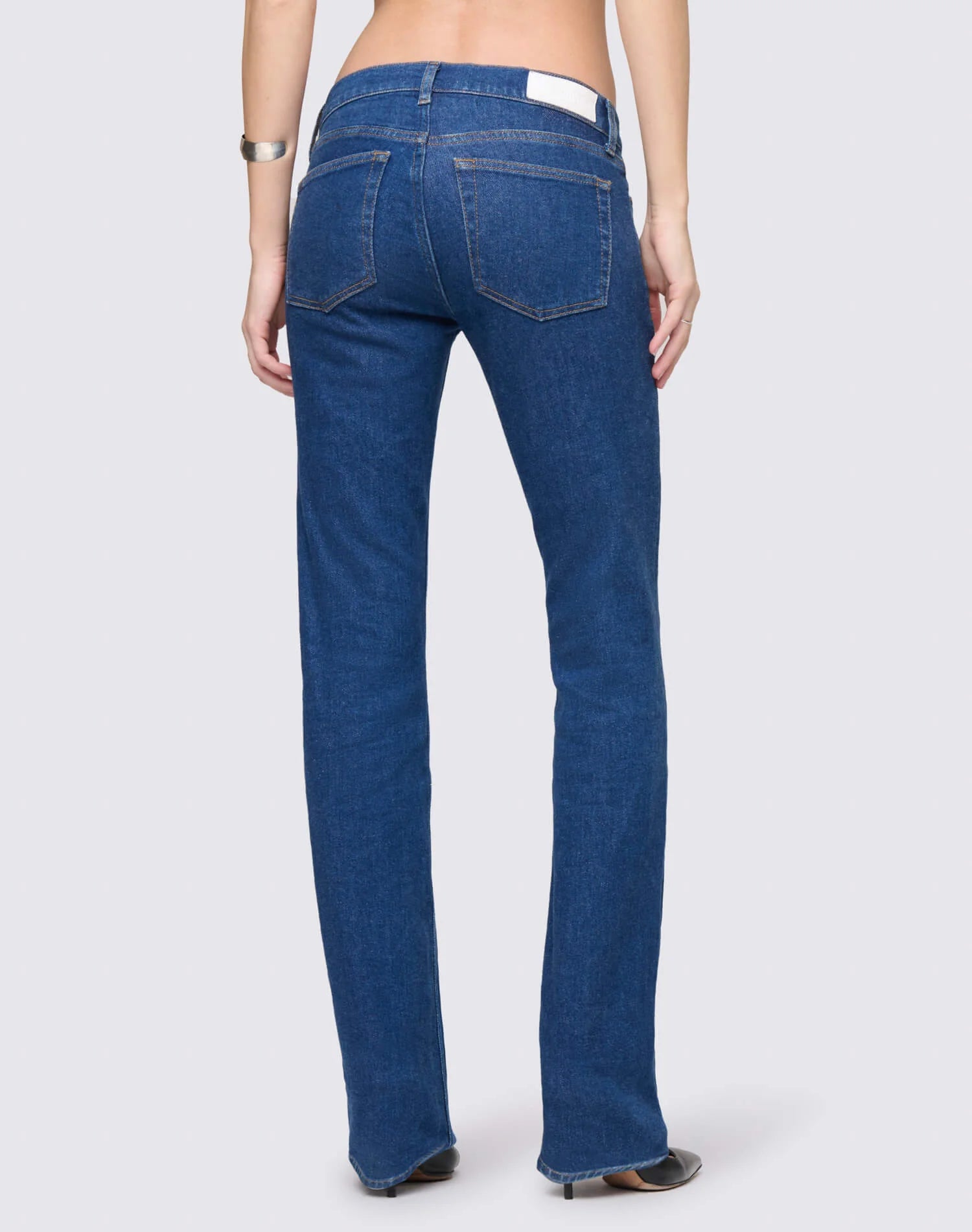 Woman wearing Re/Done dark blue straight-leg jeans with white label, shown from behind in a studio setting.