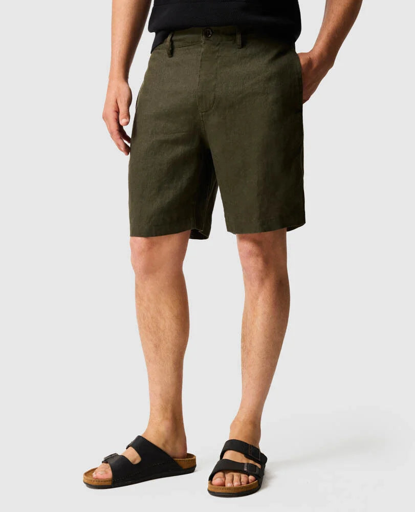 Rodd & Gunn men's dark olive linen resort shorts worn with black sandals on white background