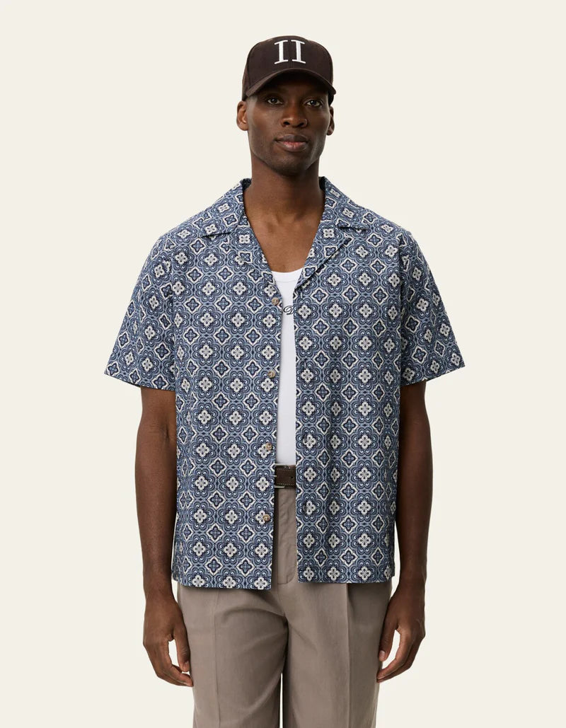 Les Deux men's short-sleeve button-up shirt with geometric arabesque pattern in blue, worn open over white tee