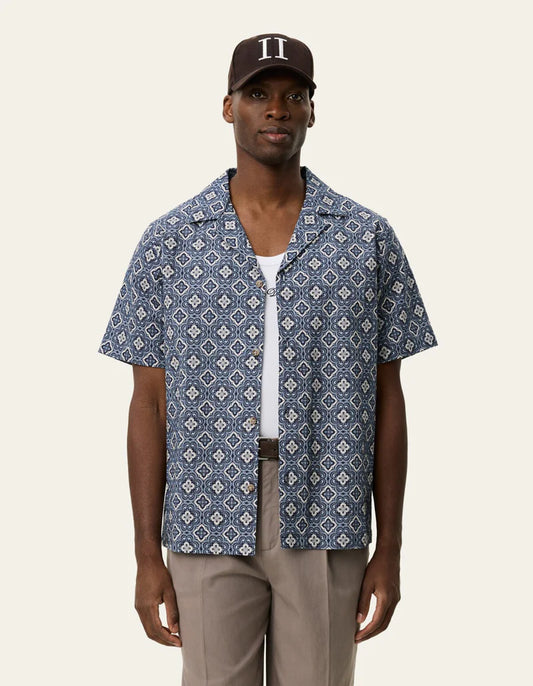 Les Deux men's short-sleeve button-up shirt with geometric arabesque pattern in blue, worn open over white tee