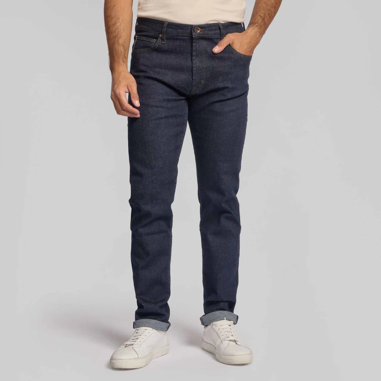 Man wearing Rye 51 Candiani Italian stretch selvedge denim jeans in slim fit with cuffed hem and white sneakers.