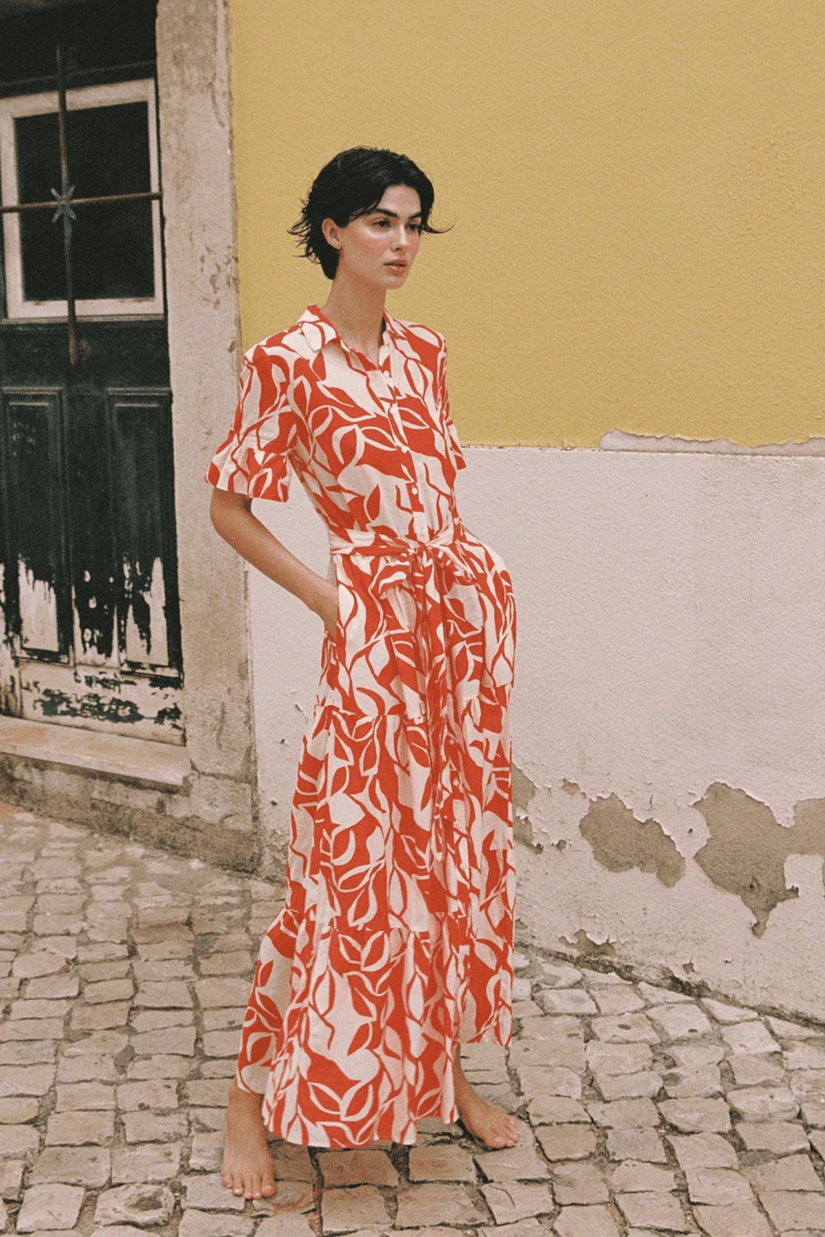 Trovata Martine Dress in red and white leaf print, featuring short sleeves, midi length, and tie waist belt.