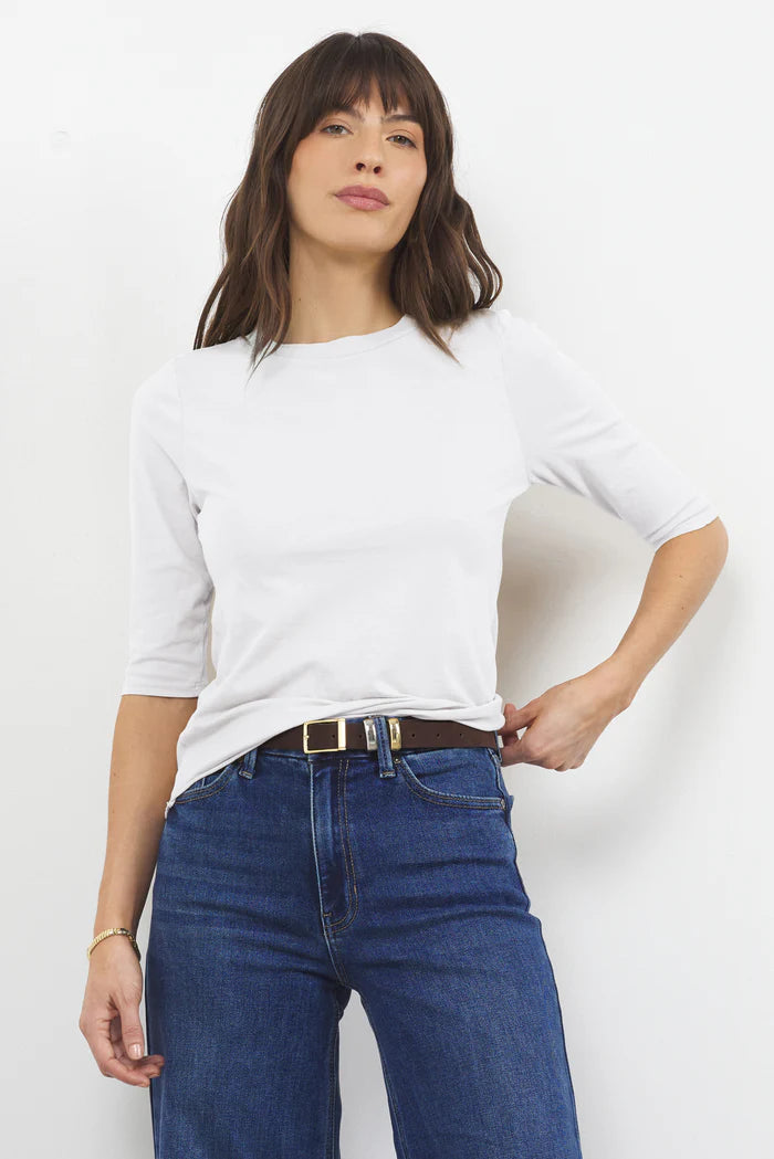 Woman wearing LAmade Santa Monica white elbow-length tee with blue jeans and belt in casual pose.