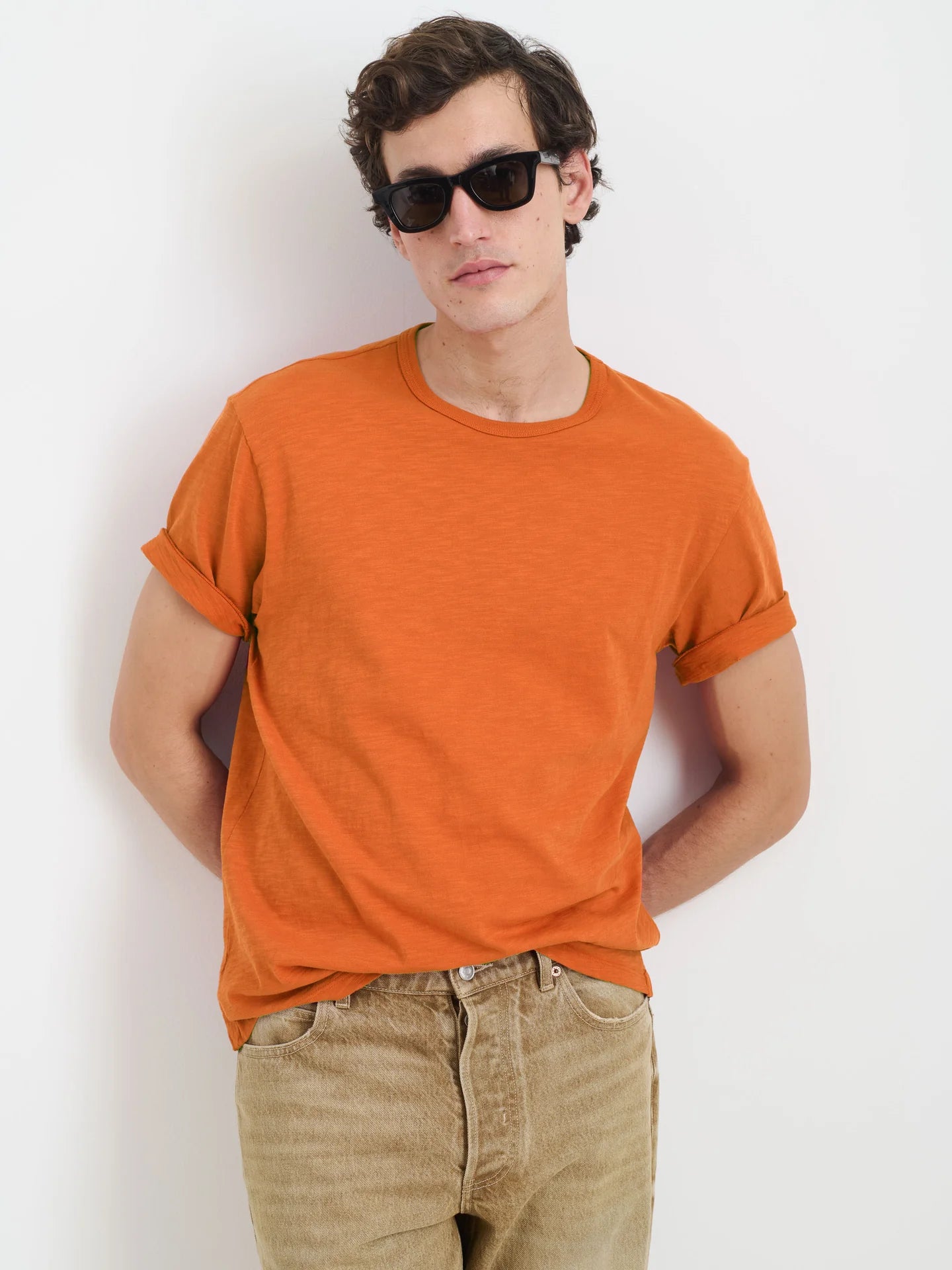 Alex Mill Standard orange slub cotton t-shirt worn by model with sunglasses and beige pants against white background.