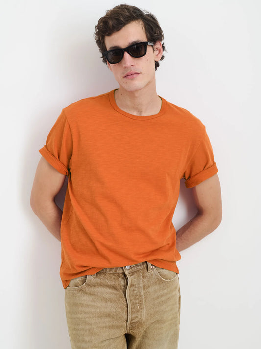 Alex Mill Standard orange slub cotton t-shirt worn by model with sunglasses and beige pants against white background.