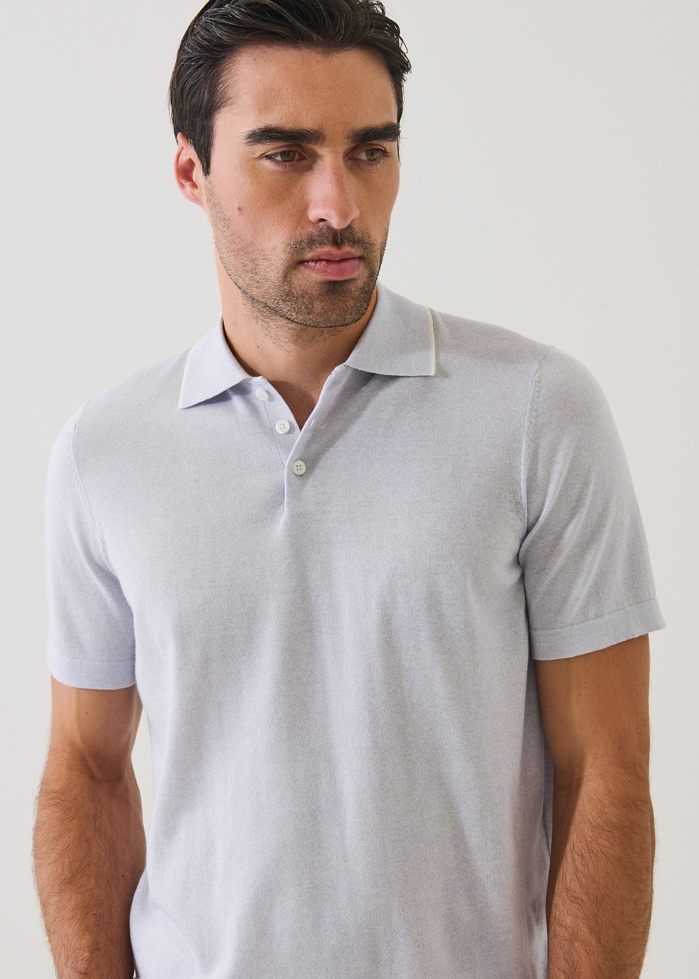 Man wearing Patrick Assaraf short-sleeve knit polo sweater with collar and button placket in light neutral tone.
