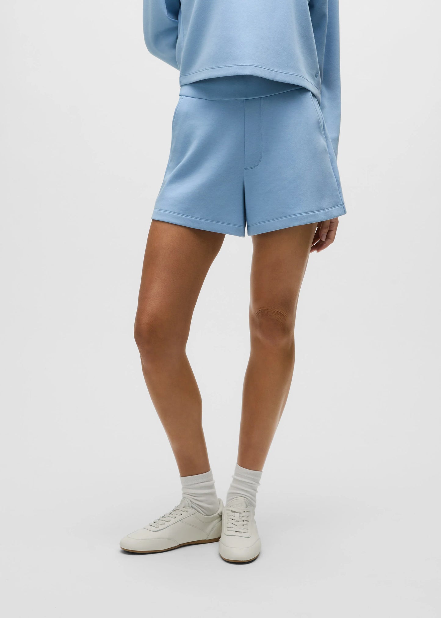 Model wearing light blue Greyson Ojai Trouser Short with matching sweatshirt and white sneakers