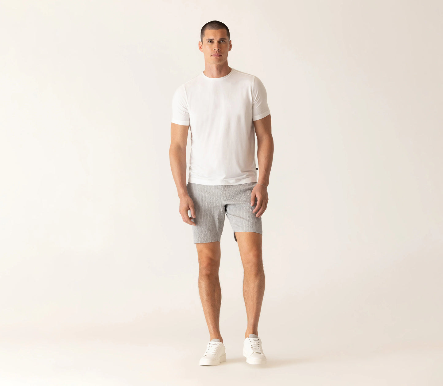 Male model wearing Deke SS Modern crew neck t-shirt in white with gray shorts and white sneakers.