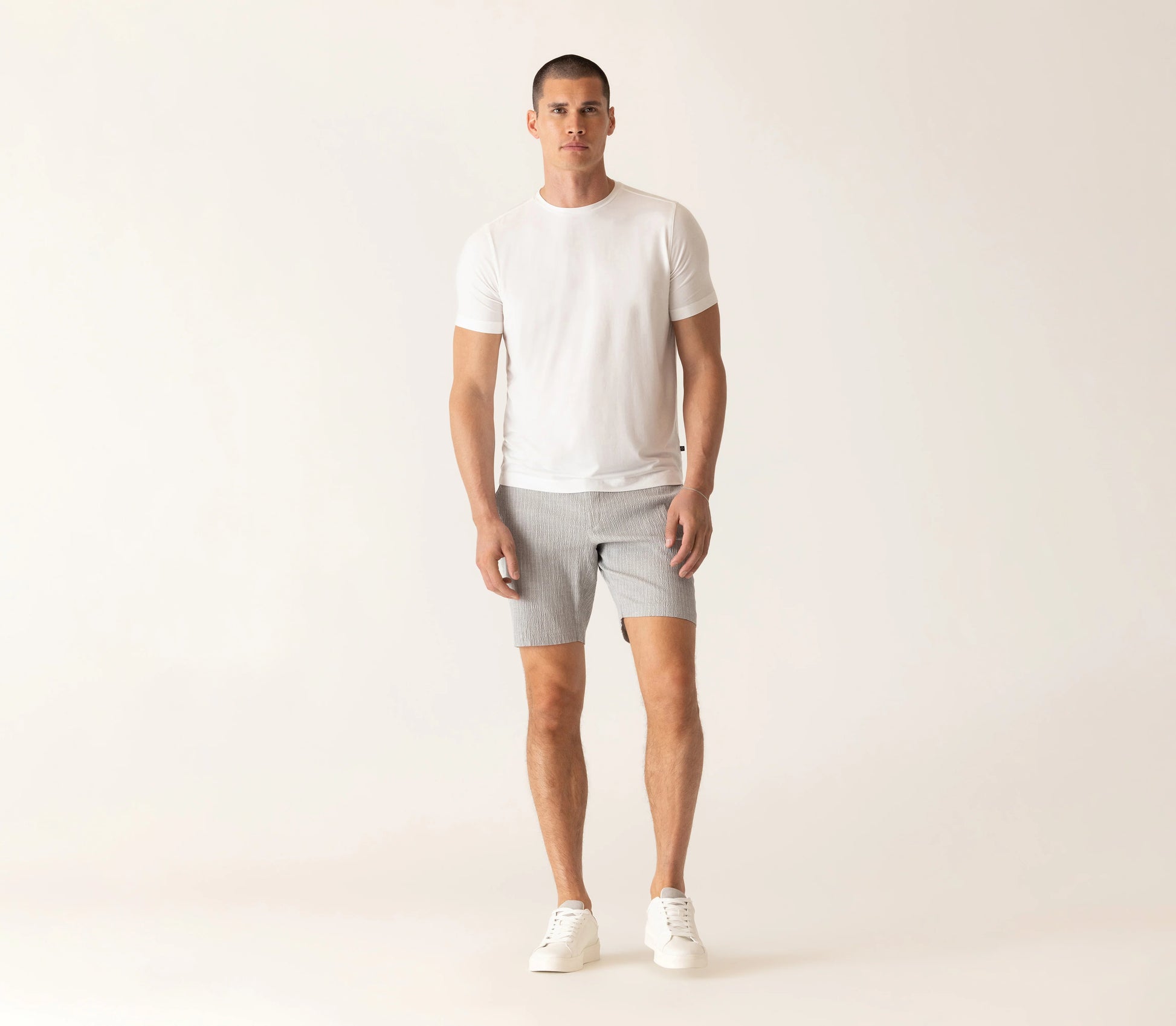 Male model wearing Deke SS Modern crew neck t-shirt in white with gray shorts and white sneakers.