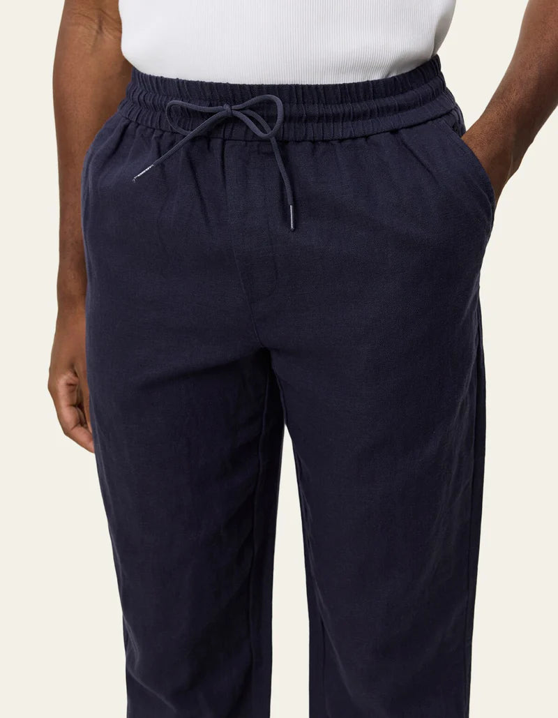 Les Deux Patrick dark navy linen pants with elastic waistband and drawstring ties, worn with white top.