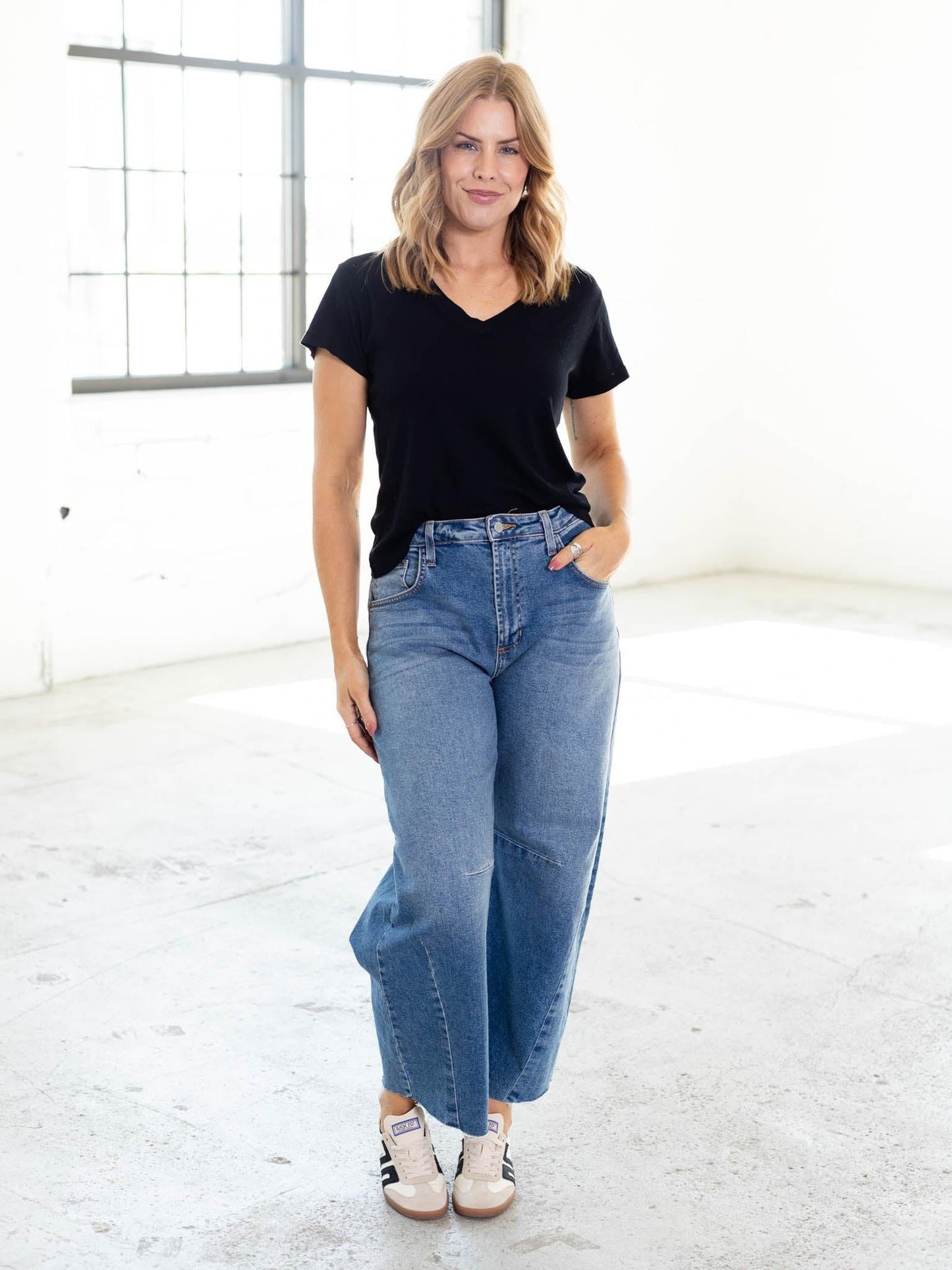 Woman wearing black v-neck t-shirt with jeans in bright studio setting