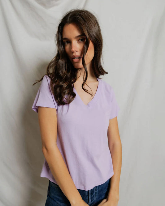 Woman wearing lavender v-neck short sleeve tee against white backdrop