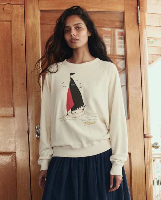 The GREAT College Sweatshirt featuring sailing boat applique design in washed white, worn with navy skirt.