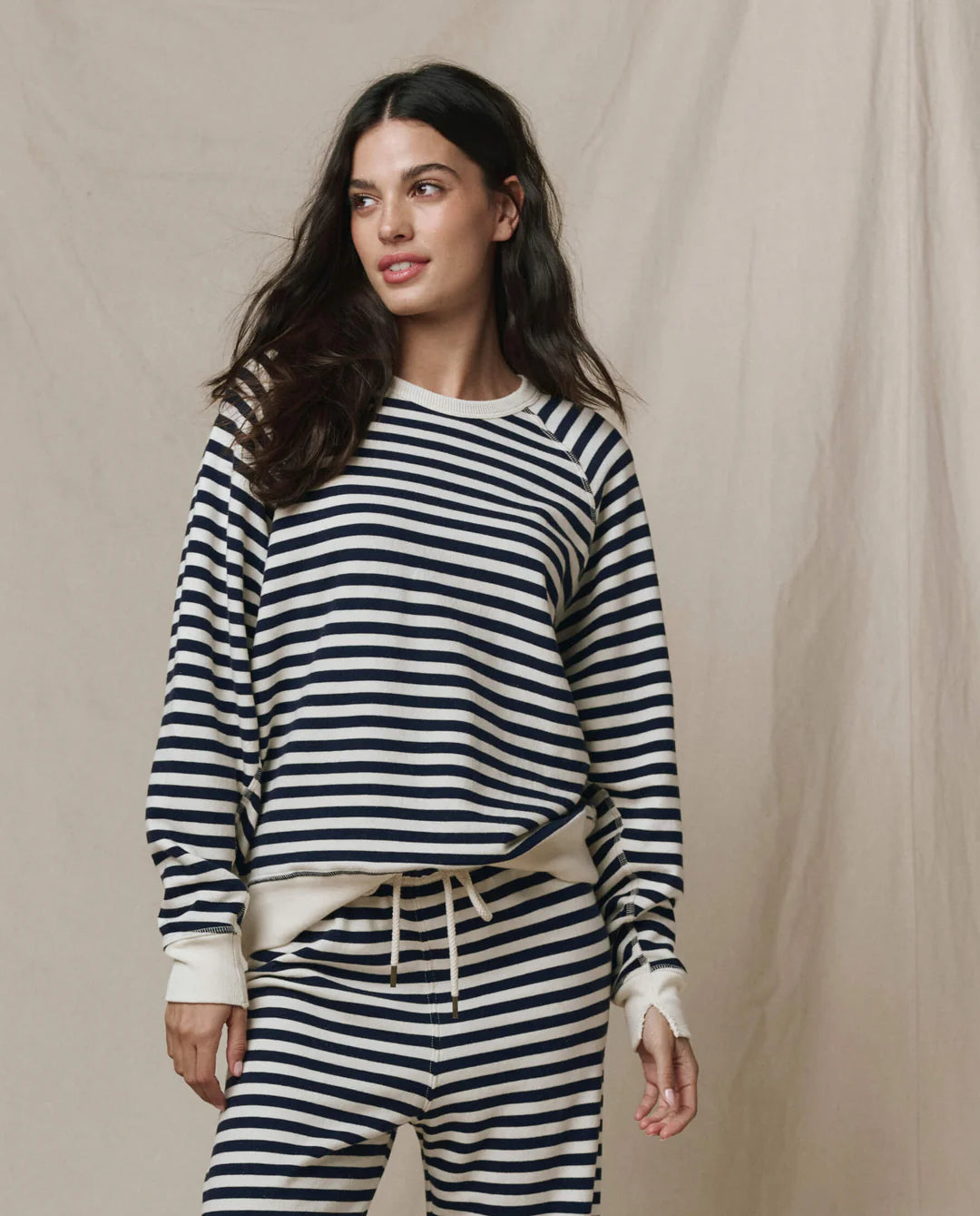 Woman wearing The GREAT College Sweatshirt in navy and white sailor stripes with matching striped joggers