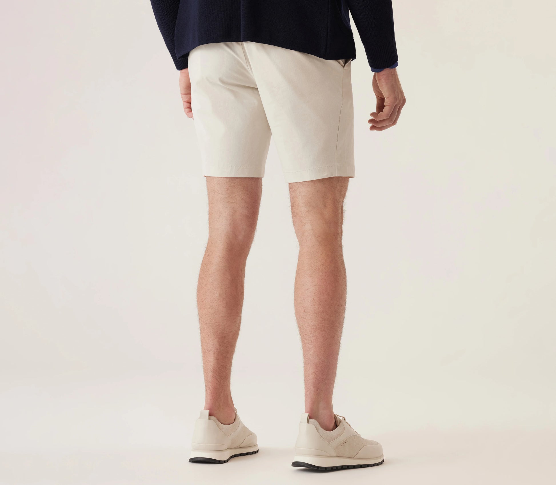 Man wearing light-colored Deke Galaxy Bermuda shorts in Ultra 4X Stretch Twill with casual sneakers.