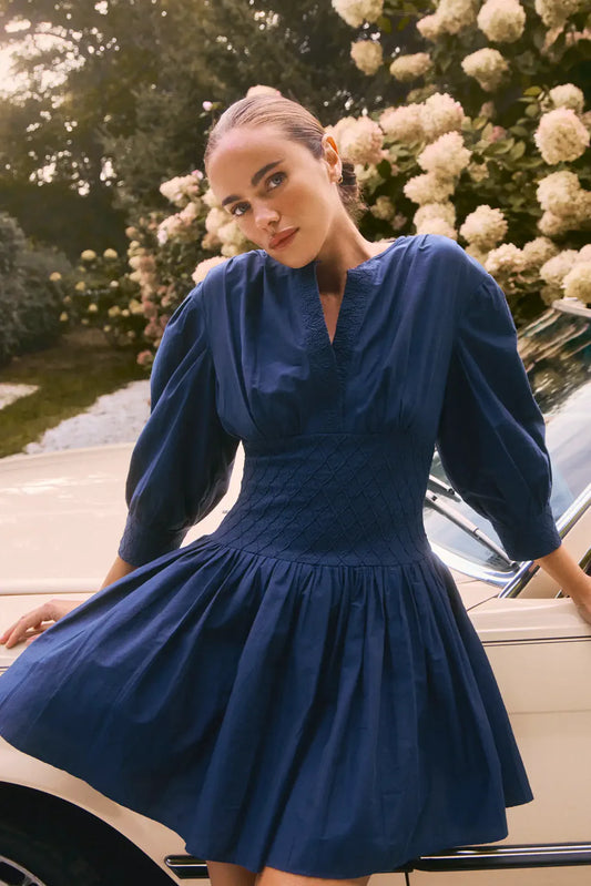 Hunter Bell Siri navy blue midi dress with puffed sleeves, smocked bodice, and flowy tiered skirt on model.