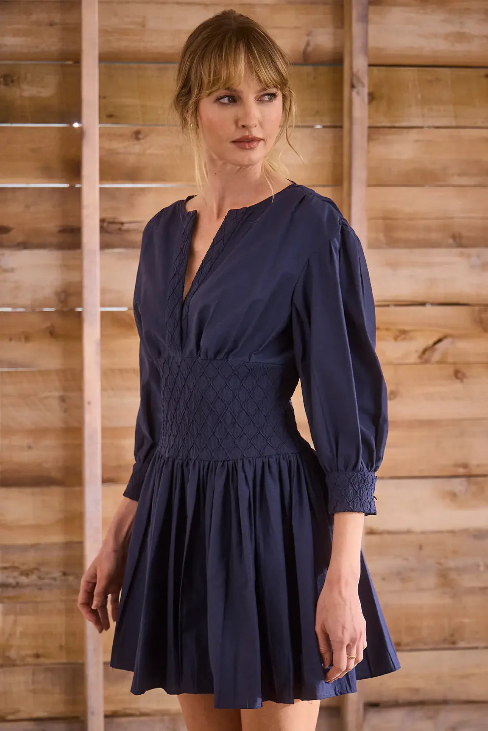 Hunter Bell Siri Dress in navy featuring smocked waist detail, long sleeves, and flowing mini skirt silhouette.
