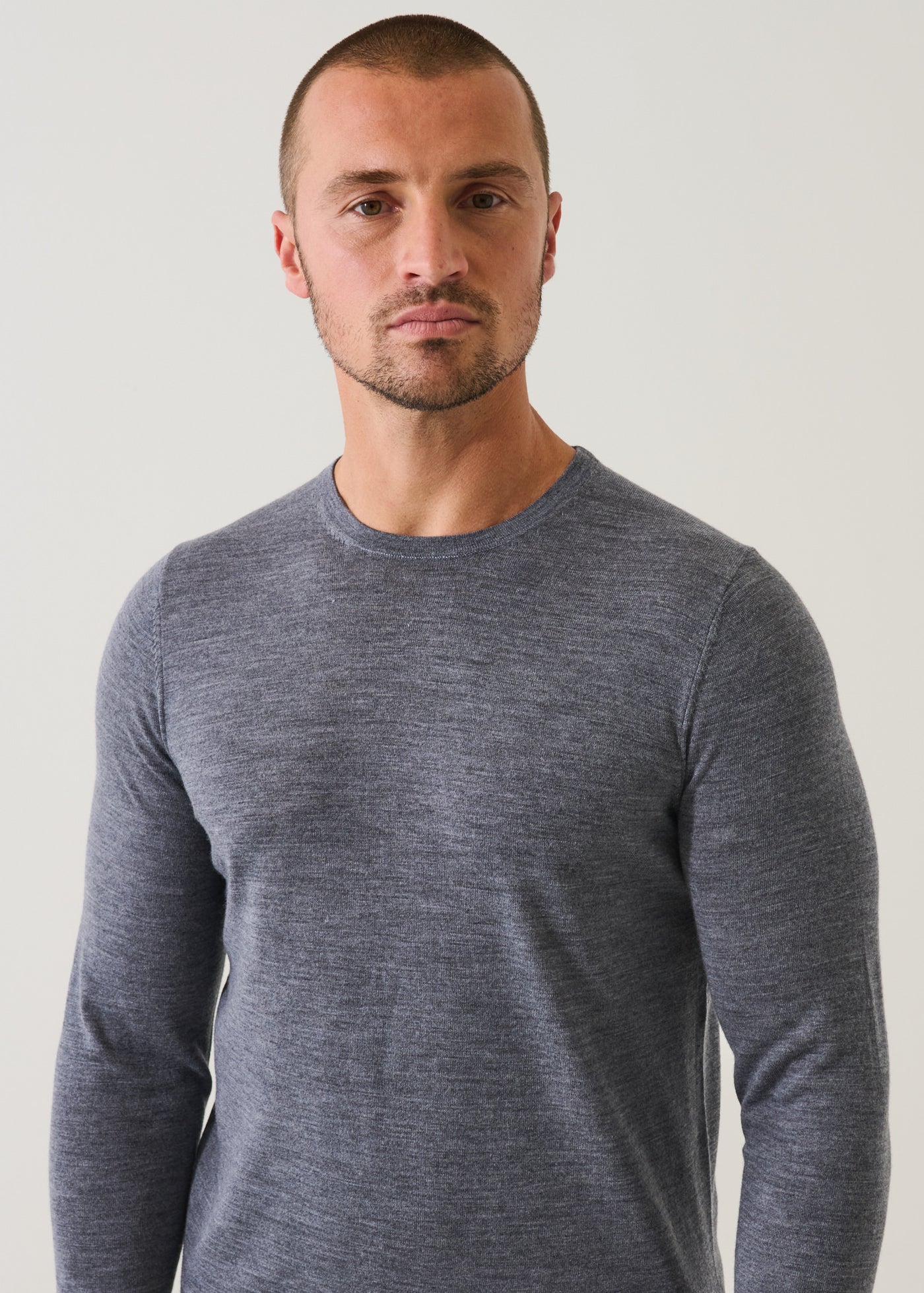 Man wearing Patrick Assaraf fine merino wool crew neck sweater in heathered grey against neutral background.