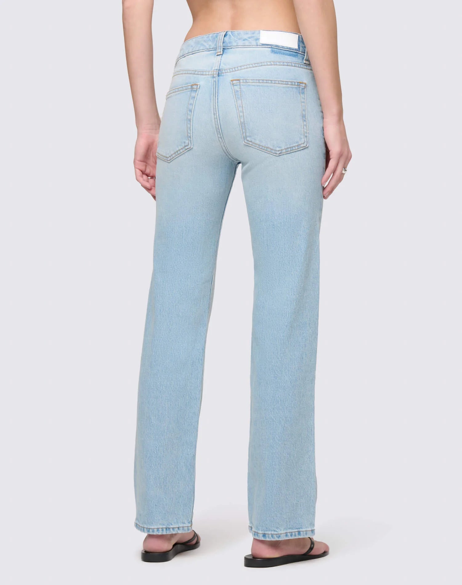 Re/Done Slim Straight Crop jeans in light wash denim, shown from behind on model wearing sandals.