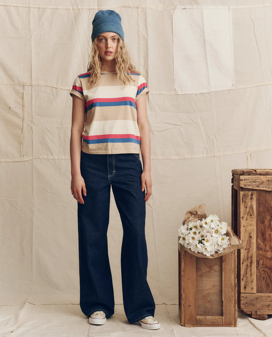 Woman wearing The Great striped short-sleeve tee with wide-leg jeans and blue beanie in casual outfit styling.