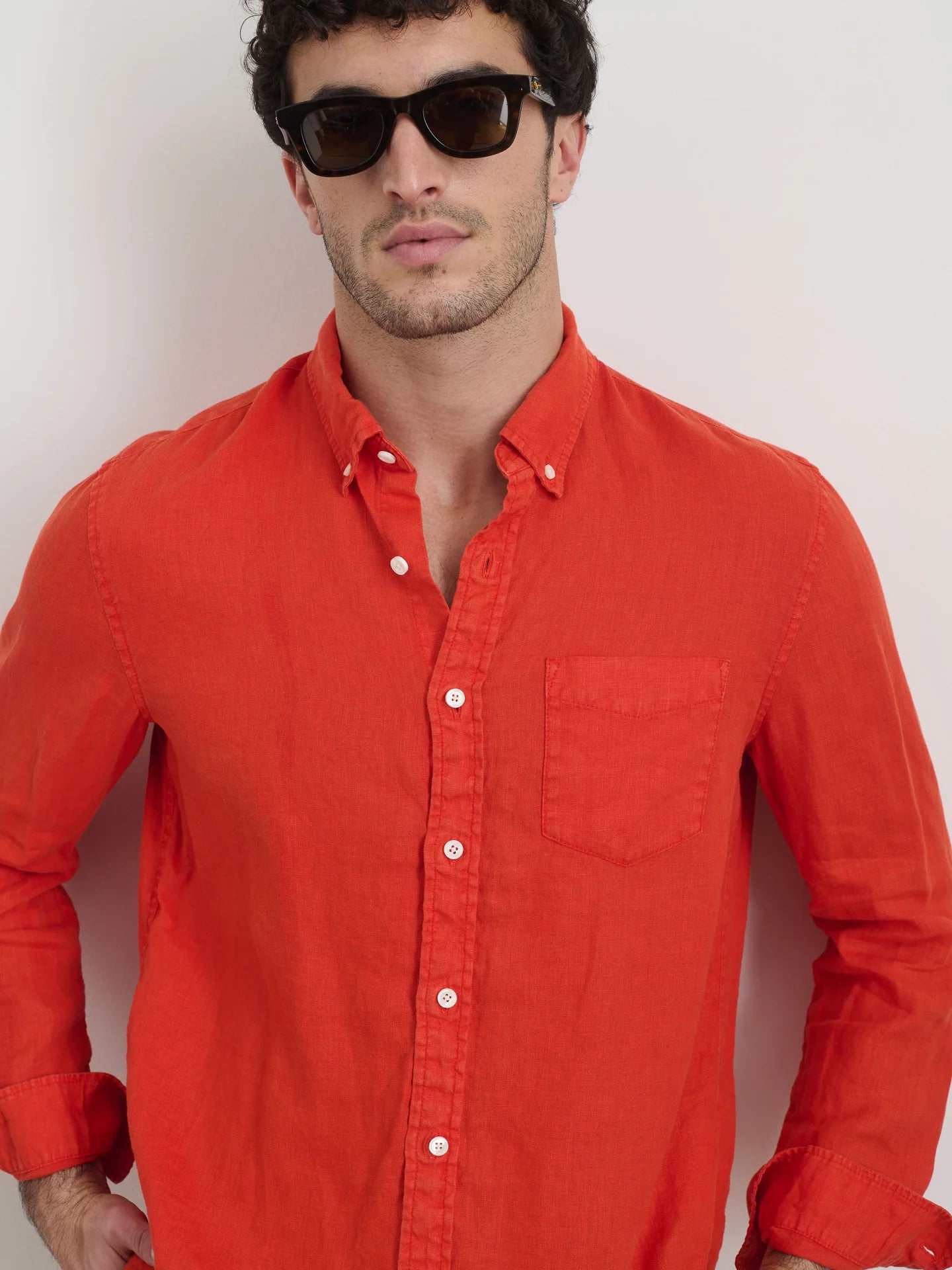 Man wearing Alex Mill orange linen button-down shirt with chest pocket and sunglasses against white background.