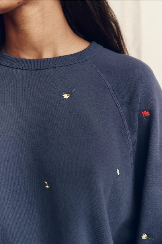 The Great navy blue college sweatshirt featuring small embroidered floral details scattered across the fabric.