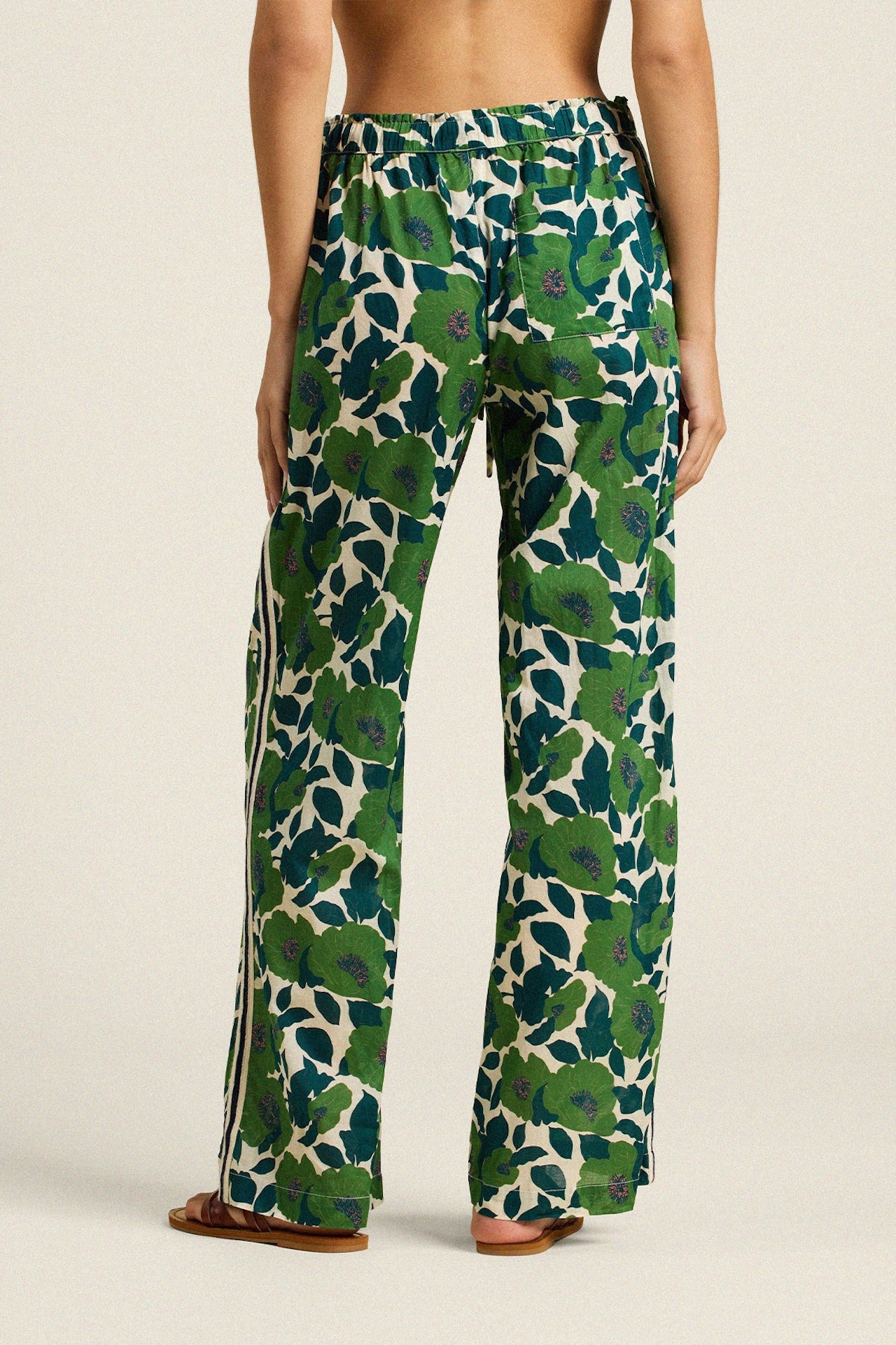 Woman wearing wide leg pants with green and navy floral print on cream background