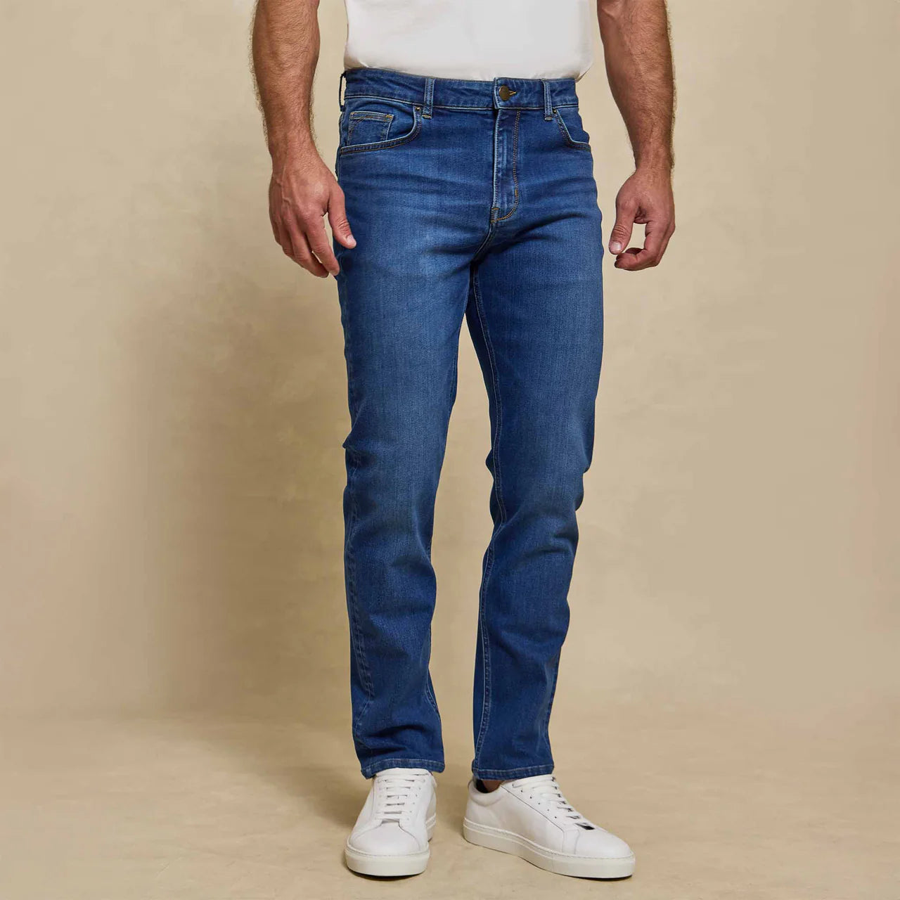 Man wearing Rye 51 Stretch blue denim jeans in Verona wash with white sneakers and t-shirt.
