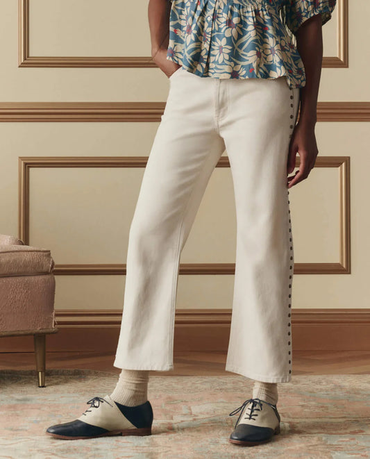 The Great studded white cropped jeans with decorative button details along the side seam, worn with oxford shoes.