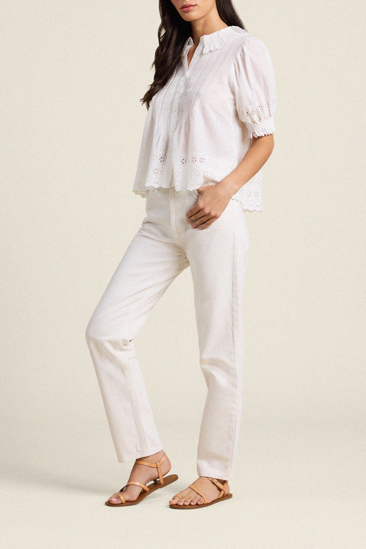 Woman wearing white eyelet blouse with lace trim and white pants in studio setting