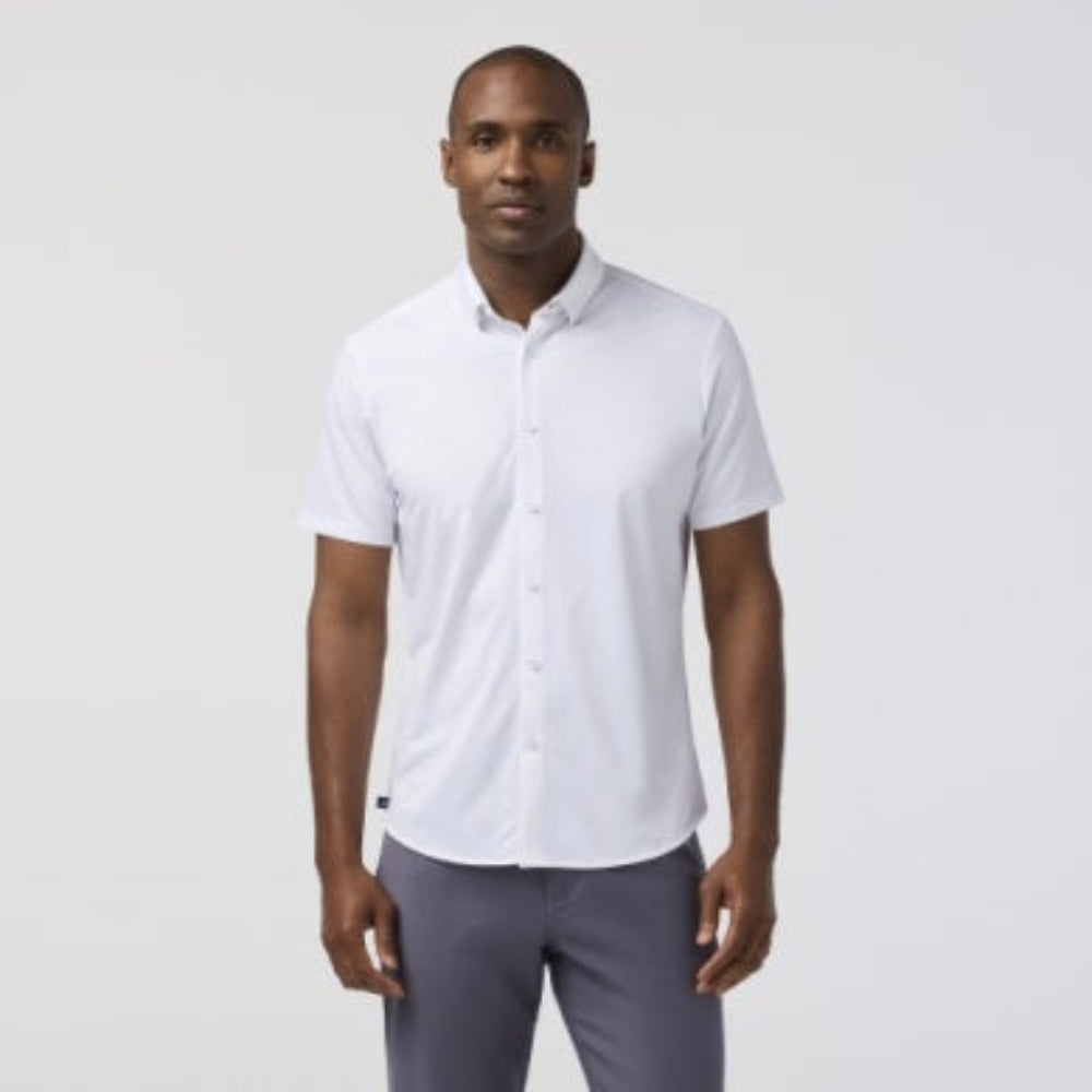 Man wearing white short sleeve collared shirt with gray pants on neutral background