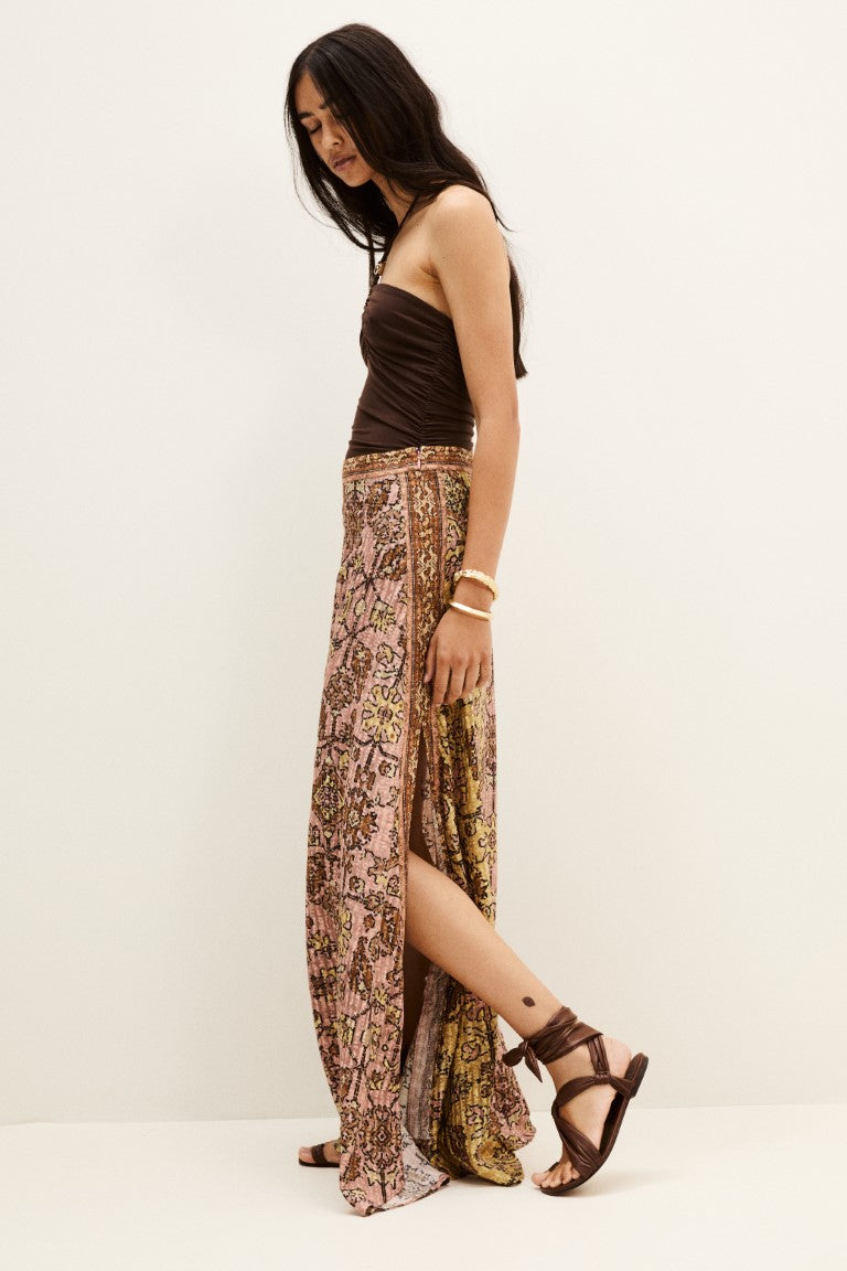 Model wearing brown strapless top and pink patterned maxi skirt with slit and brown sandals
